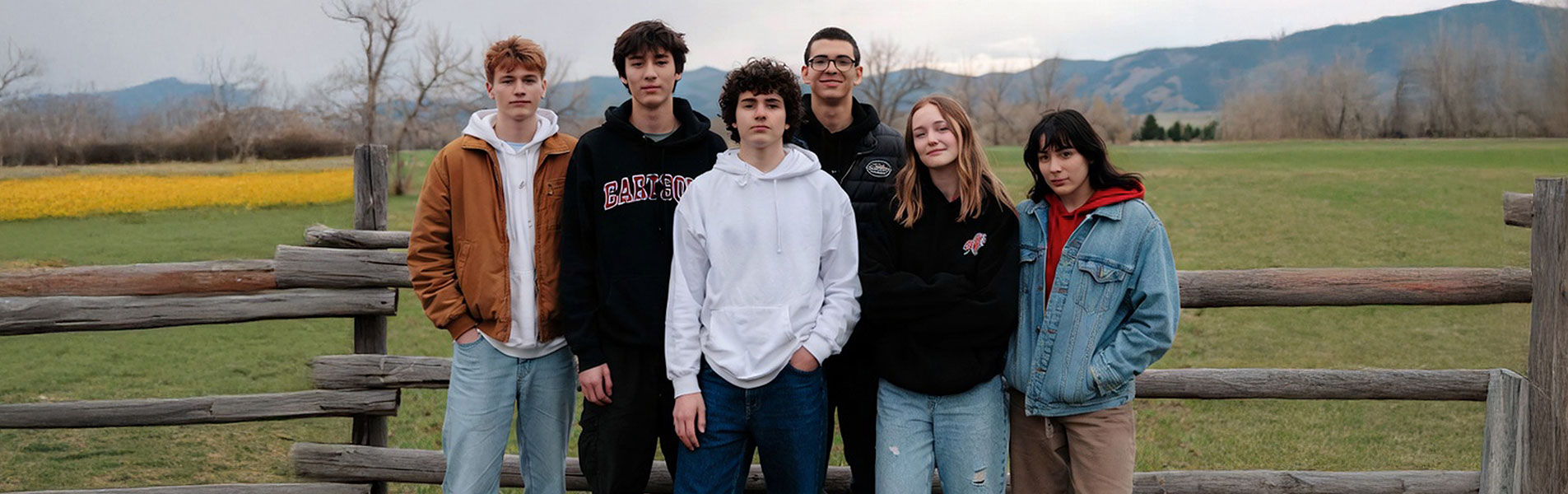Six young adults pose for a photo with beautiful Montana background