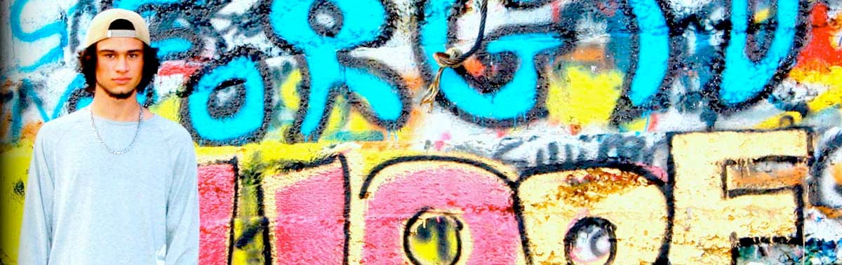 Young adult standing in front of graffiti that reads Forgive and Hope